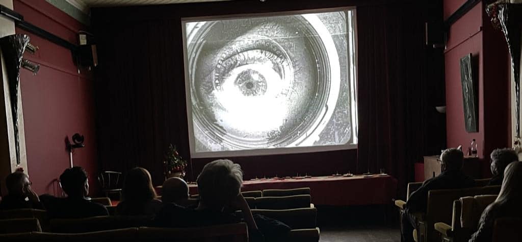 People watching screening in cinema showing an eye in close up on screen